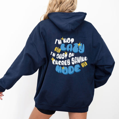Back of a hoodie with the phrase “I’m Not Lazy, I’m Just on Energy Saving Mode” in playful retro typography. Cozy, unisex fit.