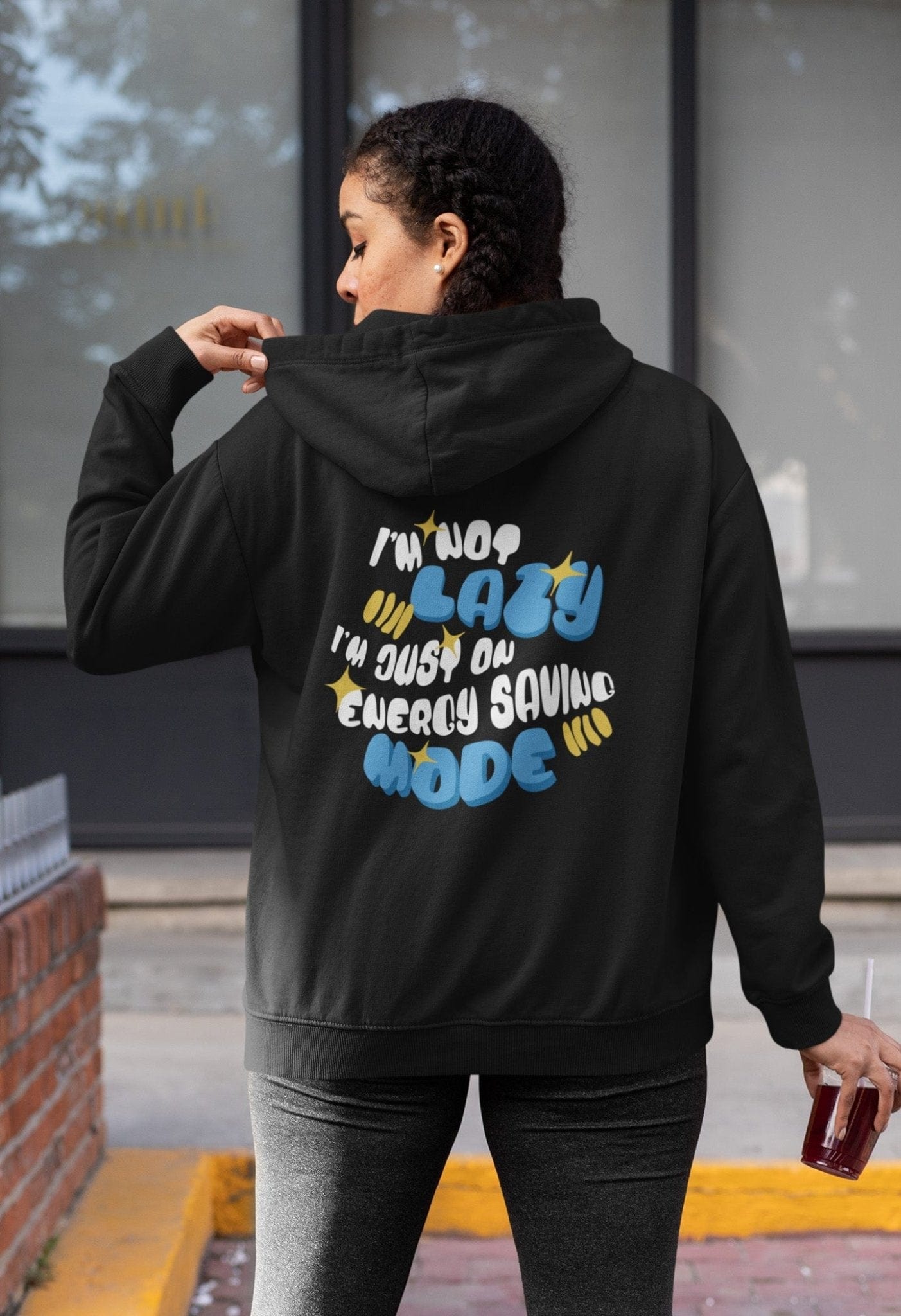 Back of a hoodie with the phrase “I’m Not Lazy, I’m Just on Energy Saving Mode” in playful retro typography. Cozy, unisex fit.