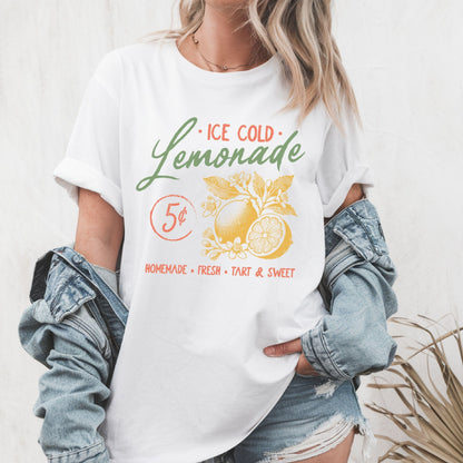 T-shirt design featuring vintage-style "Ice Cold Lemonade" text with yellow lemons, floral details, and a 5¢ sign for a retro summer vibe.