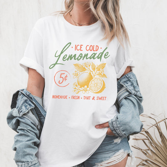 T-shirt design featuring vintage-style "Ice Cold Lemonade" text with yellow lemons, floral details, and a 5¢ sign for a retro summer vibe.