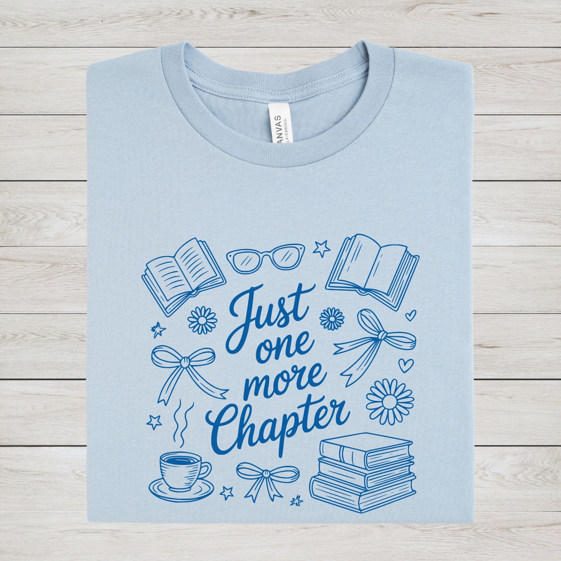 Just One More Chapter t-shirt in a cozy book lover aesthetic with bows, books, and daisies on front design