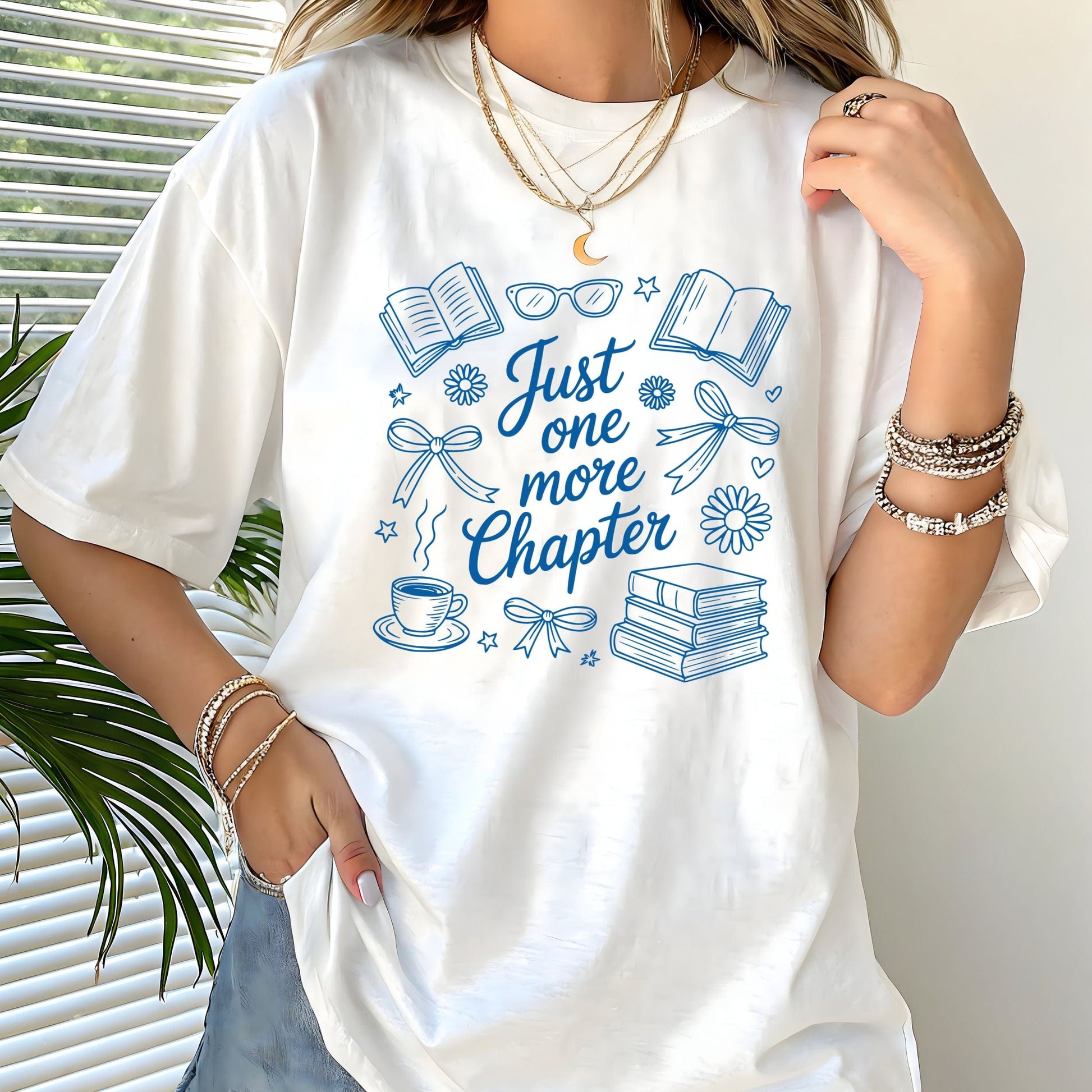 Just One More Chapter t-shirt in a cozy book lover aesthetic with bows, books, and daisies on front design