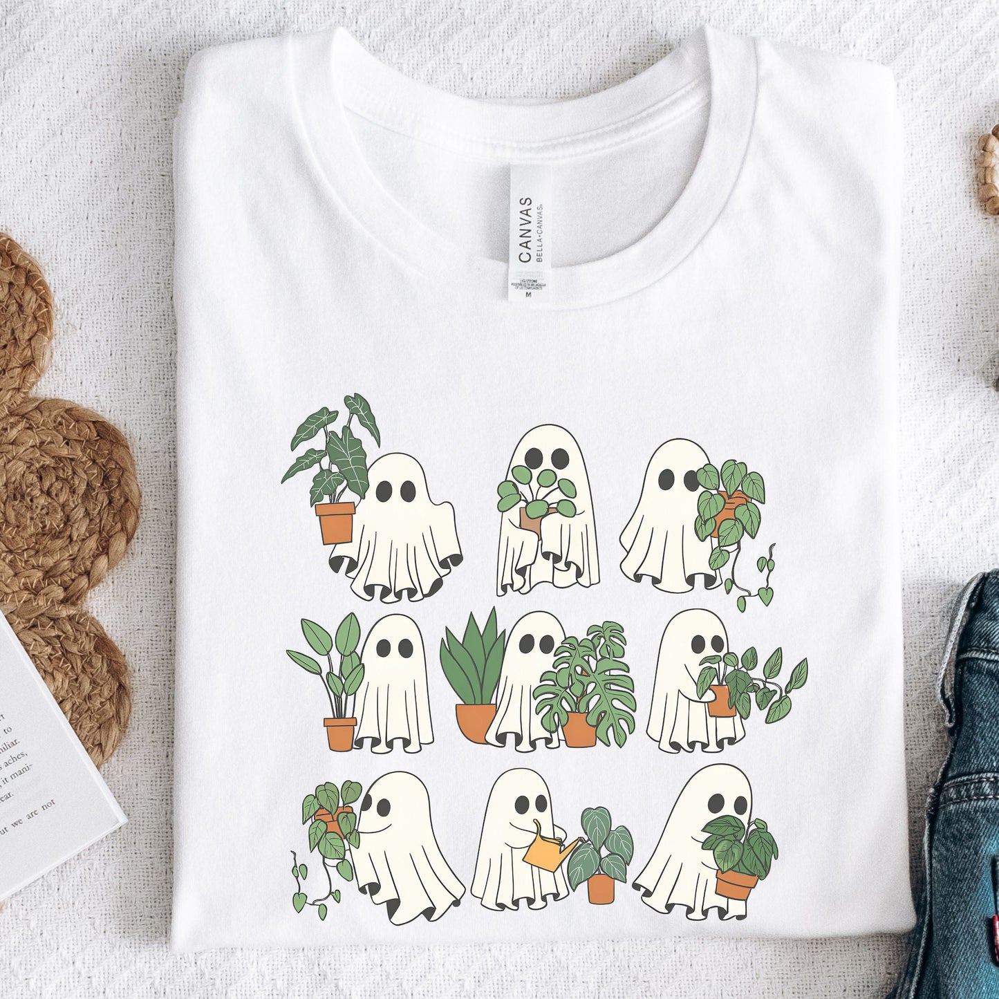White t-shirt with ghost and plant design on a textured surface