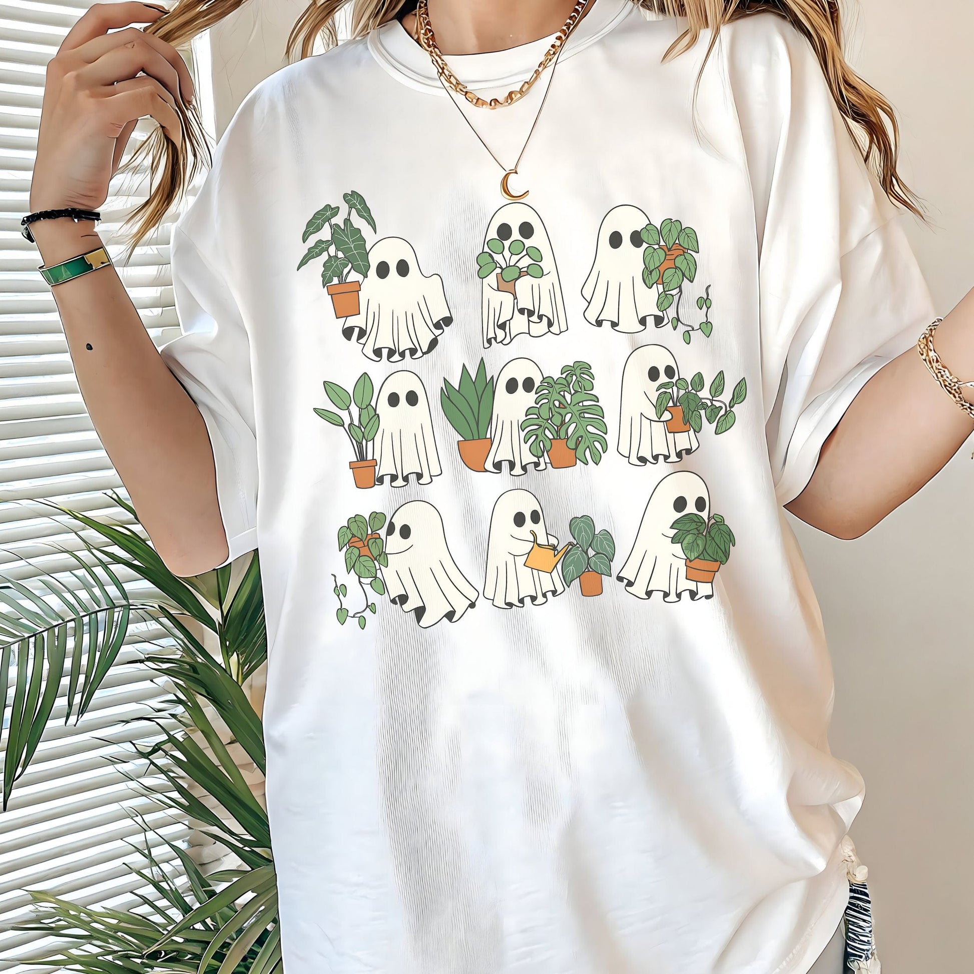 White t-shirt with ghost and plant design worn by a person, with plants in the background