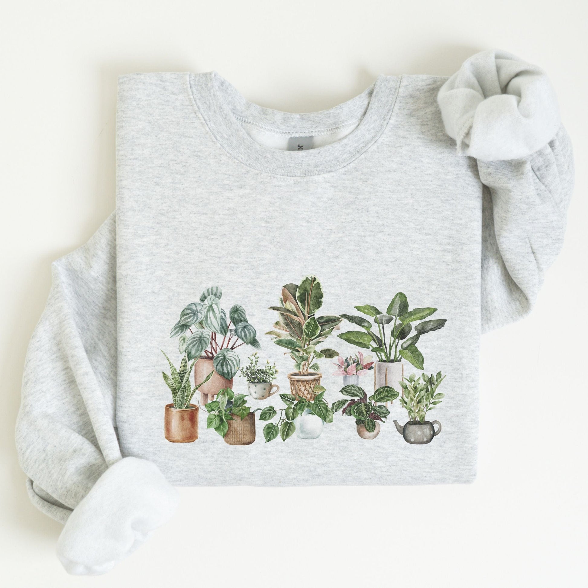 Cozy unisex sweatshirt featuring a watercolor-style houseplant graphic — perfect for plant lovers and indoor garden aesthetic fans.