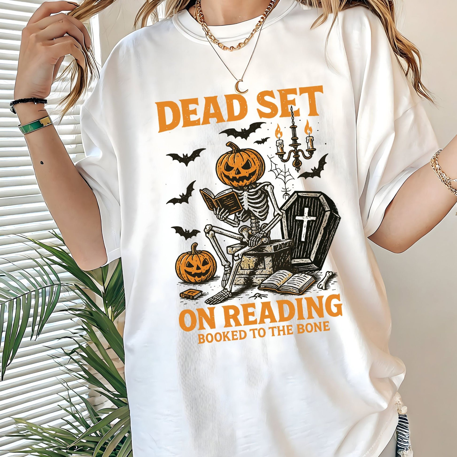 Vintage Halloween t-shirt with a skeleton reading a book, pumpkin head, bats, and spooky autumn vibe