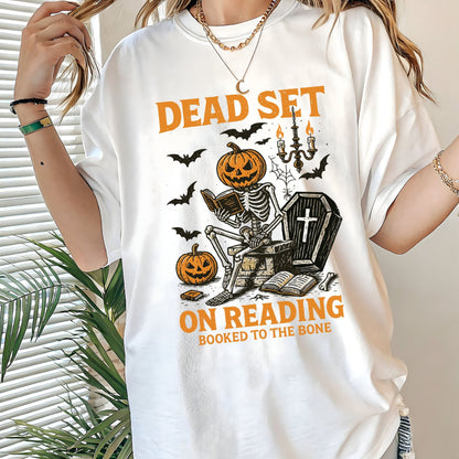 Vintage Halloween t-shirt with a skeleton reading a book, pumpkin head, bats, and spooky autumn vibe