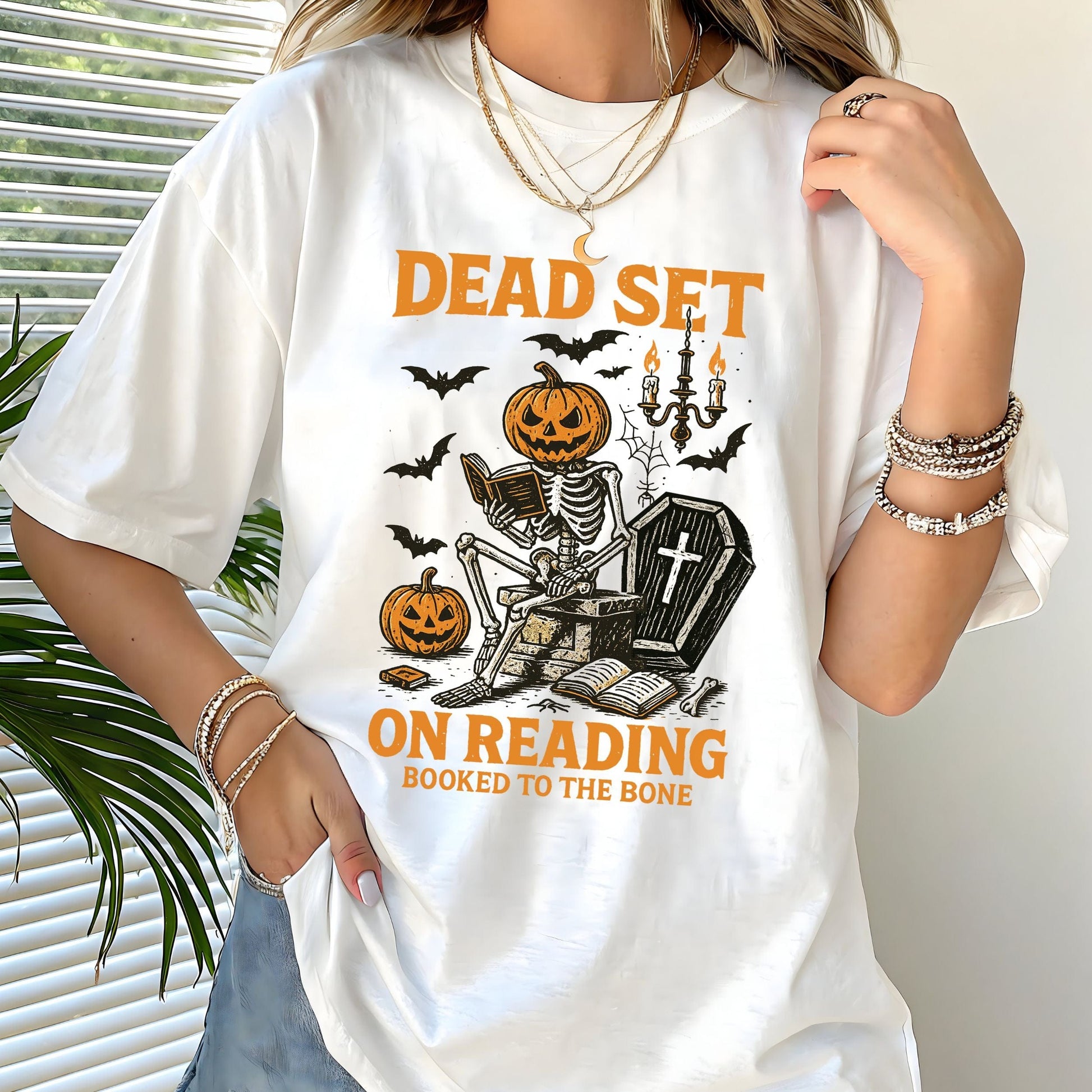 Vintage Halloween t-shirt with a skeleton reading a book, pumpkin head, bats, and spooky autumn vibe