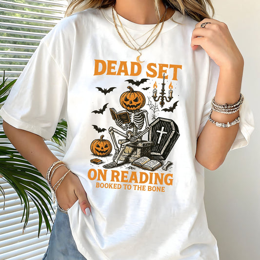 Vintage Halloween t-shirt with a skeleton reading a book, pumpkin head, bats, and spooky autumn vibe