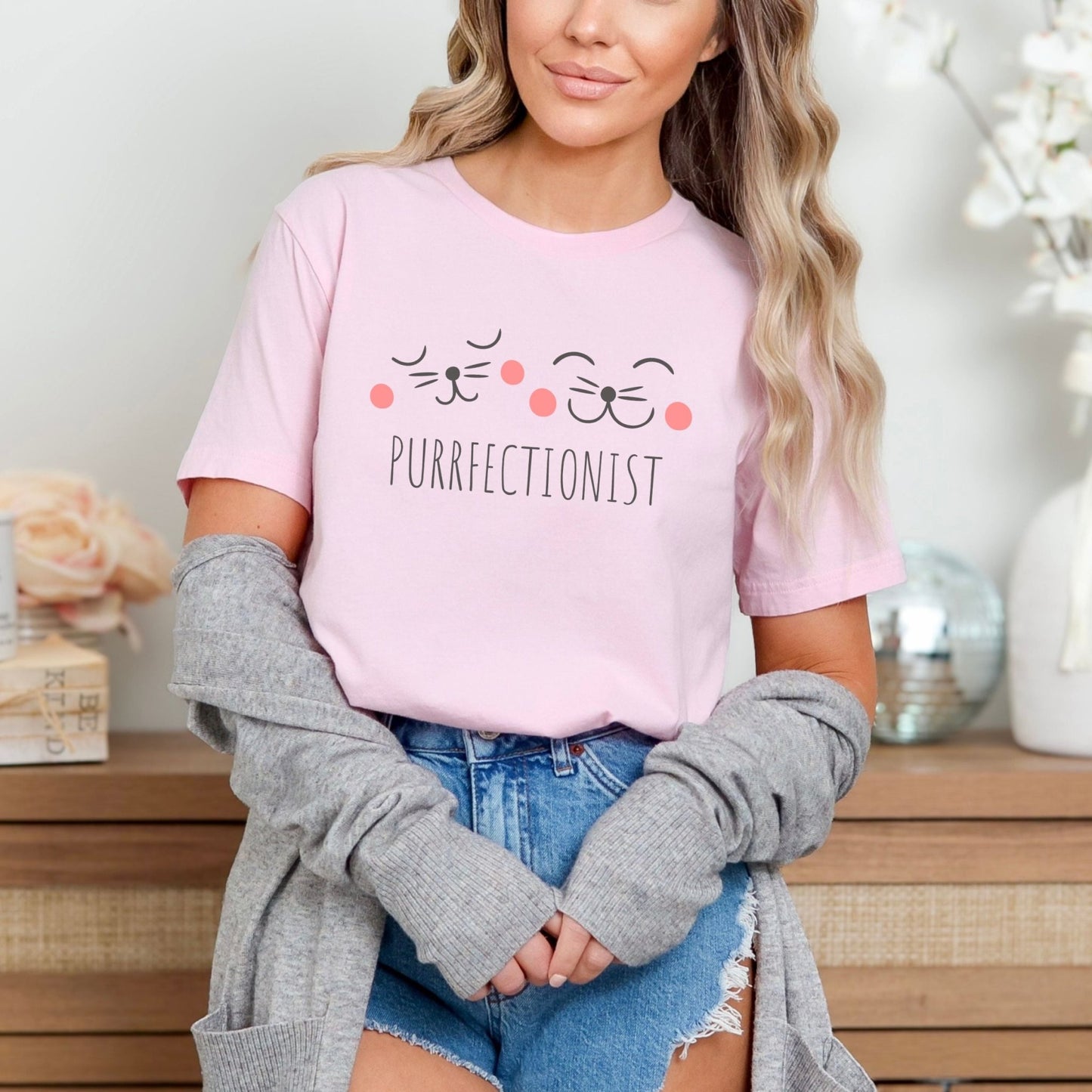 Shirt with "Purrfectionist" text and cute cat face design for cat lovers.