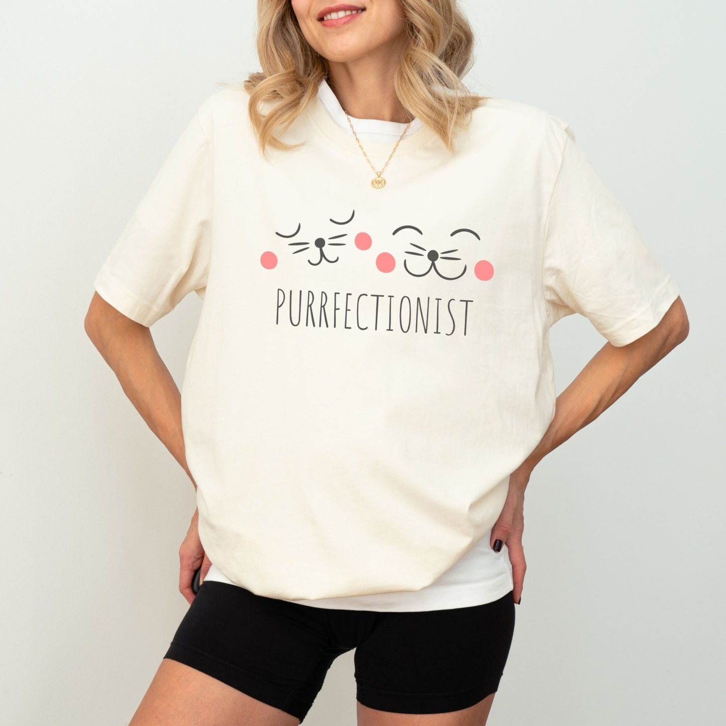 Shirt with "Purrfectionist" text and cute cat face design for cat lovers.