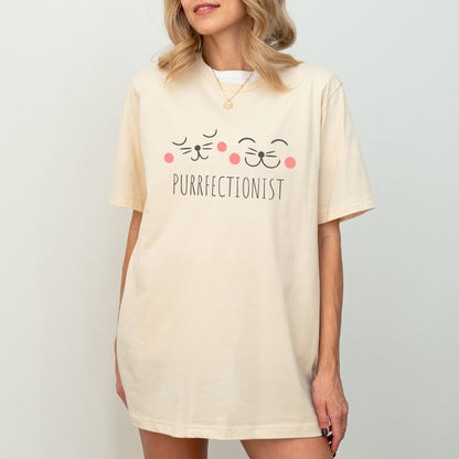 Shirt with "Purrfectionist" text and cute cat face design for cat lovers.