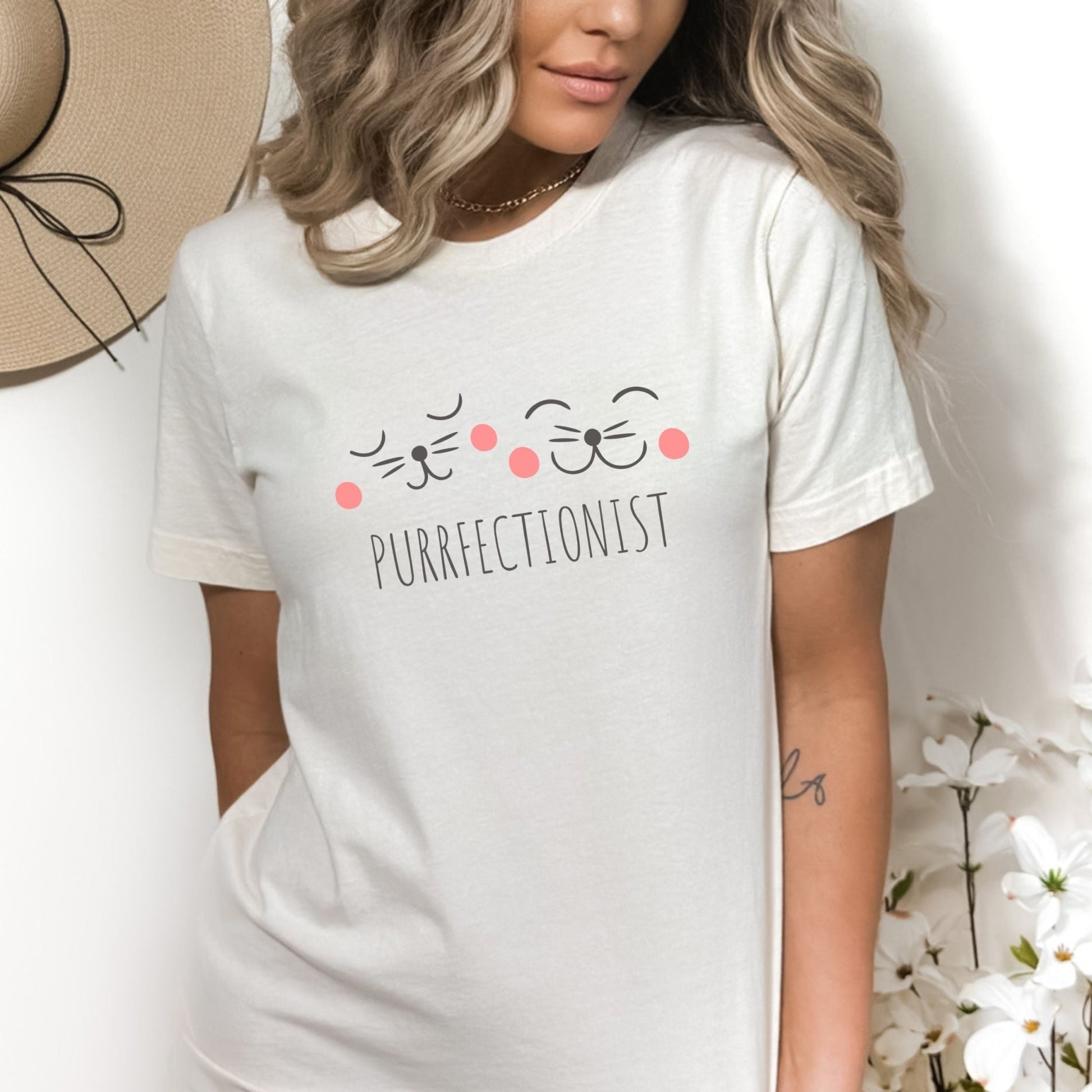 Shirt with "Purrfectionist" text and cute cat face design for cat lovers.