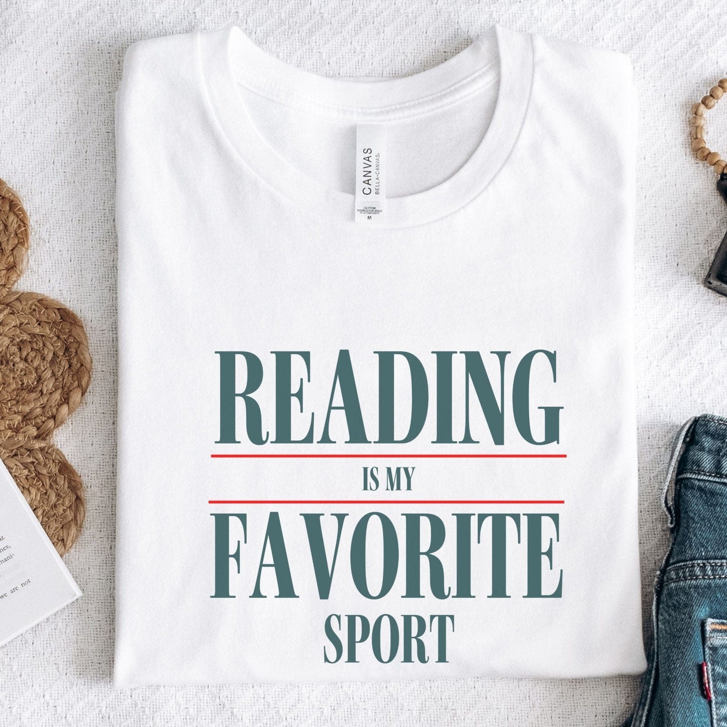 “Reading Is My Favorite Sport” t-shirt with bold serif font in dark teal and red underline accents, minimalist literary design.