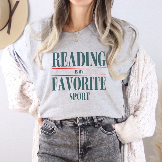 “Reading Is My Favorite Sport” t-shirt with bold serif font in dark teal and red underline accents, minimalist literary design.
