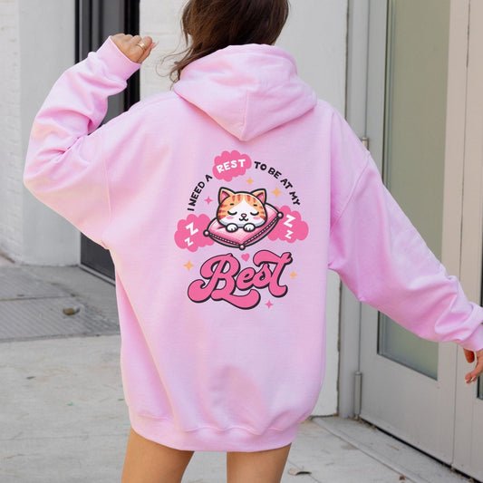 Kawaii hoodie with "Rest to Be at Your Best" back design featuring a cute cat sleeping on a pillow, and a matching mini cat graphic on the front chest.