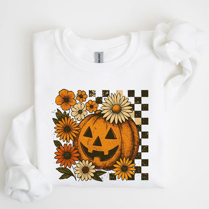 White sweatshirt with a Halloween-themed design featuring a jack-o'-lantern and flowers on a white background.