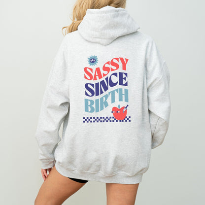 Sassy Since Birth hoodie with bold typography and colorful graphic design, cozy and available in 6 colors.