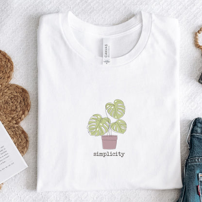 “Simplicity” t-shirt with minimalist monstera plant in a muted pink pot and soft, modern lettering beneath the design.