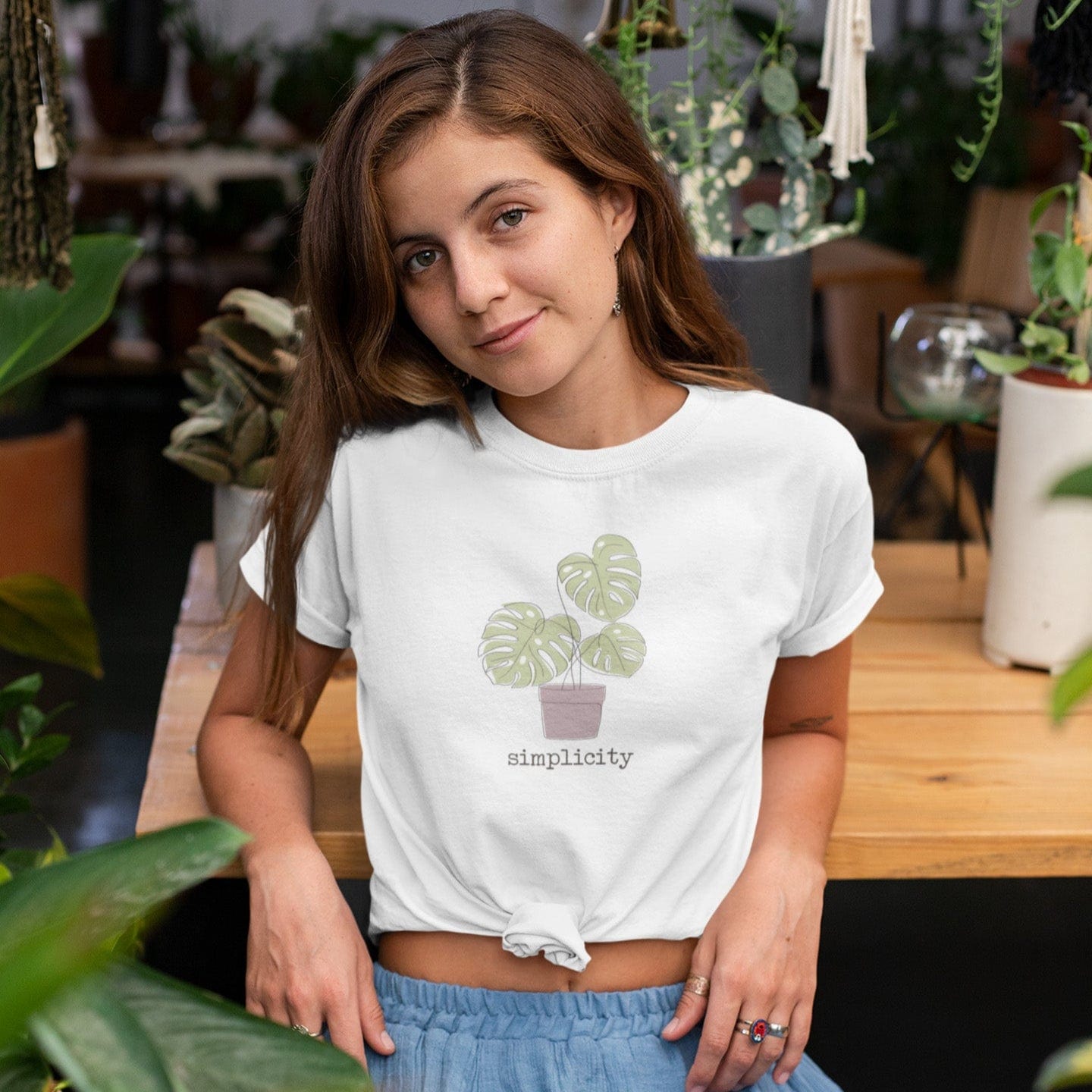 “Simplicity” t-shirt with minimalist monstera plant in a muted pink pot and soft, modern lettering beneath the design.