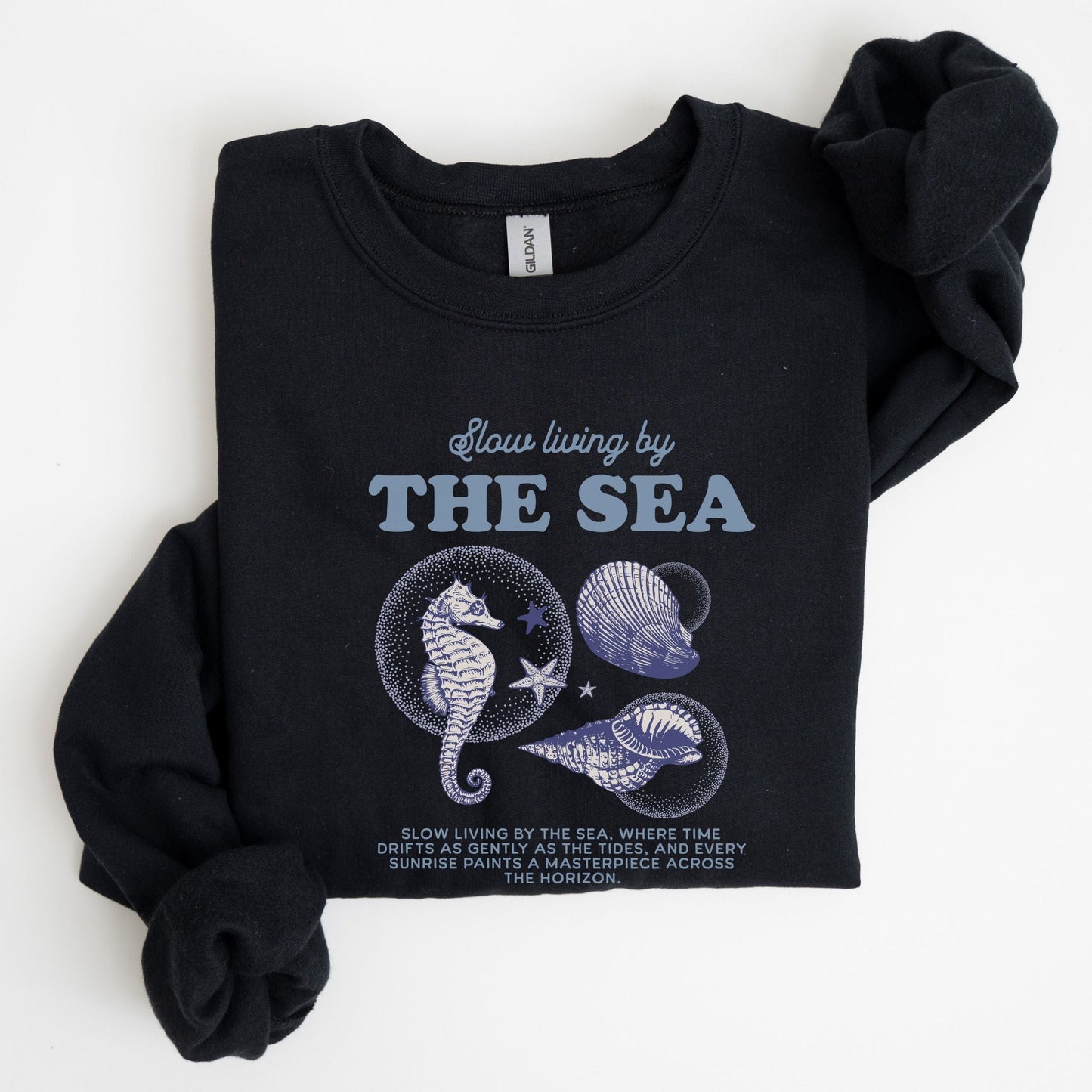 Vintage-style seahorse and seashell graphic with “Slow Living by the Sea” text on a soft unisex sweatshirt, part of the summer coastal collection.