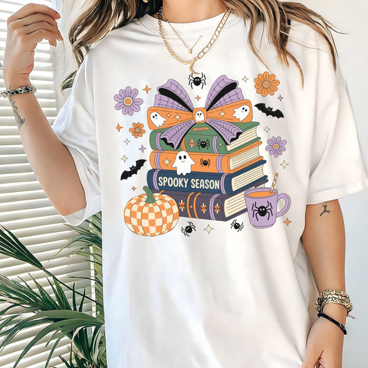 Halloween t-shirt with colorful stack of books, ghosts, pumpkin, and coffee cup reading “Spooky Season.”