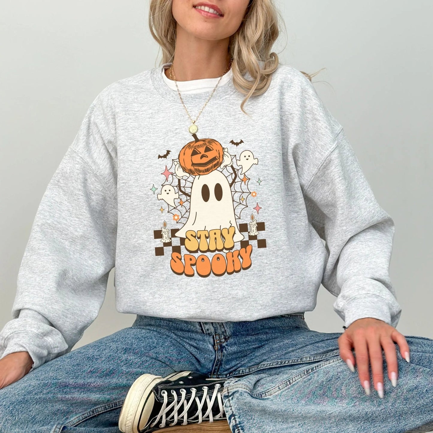 Retro "Stay Spooky" sweatshirt with ghost and pumpkin design, available in 10 colors.