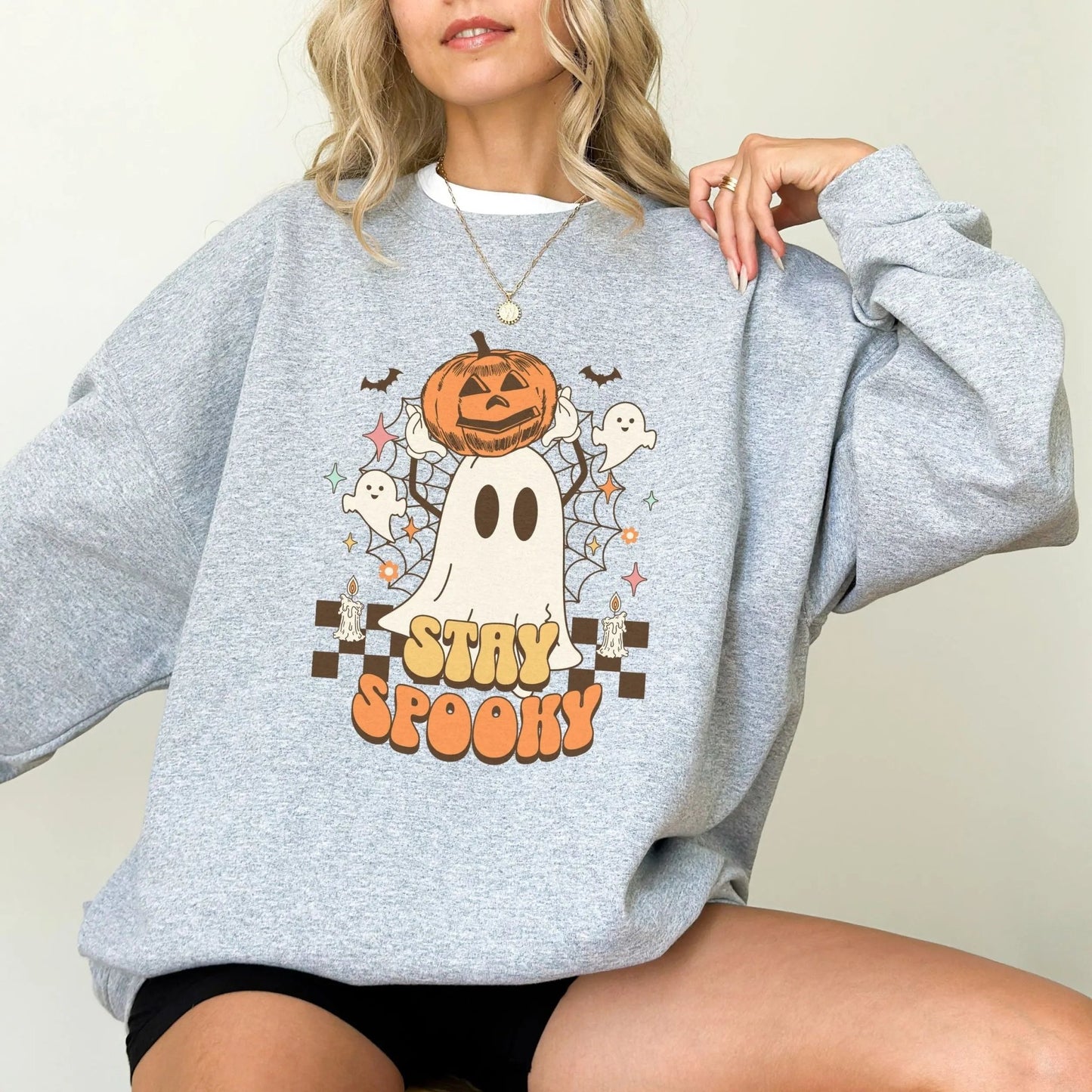 Retro "Stay Spooky" sweatshirt with ghost and pumpkin design, available in 10 colors.