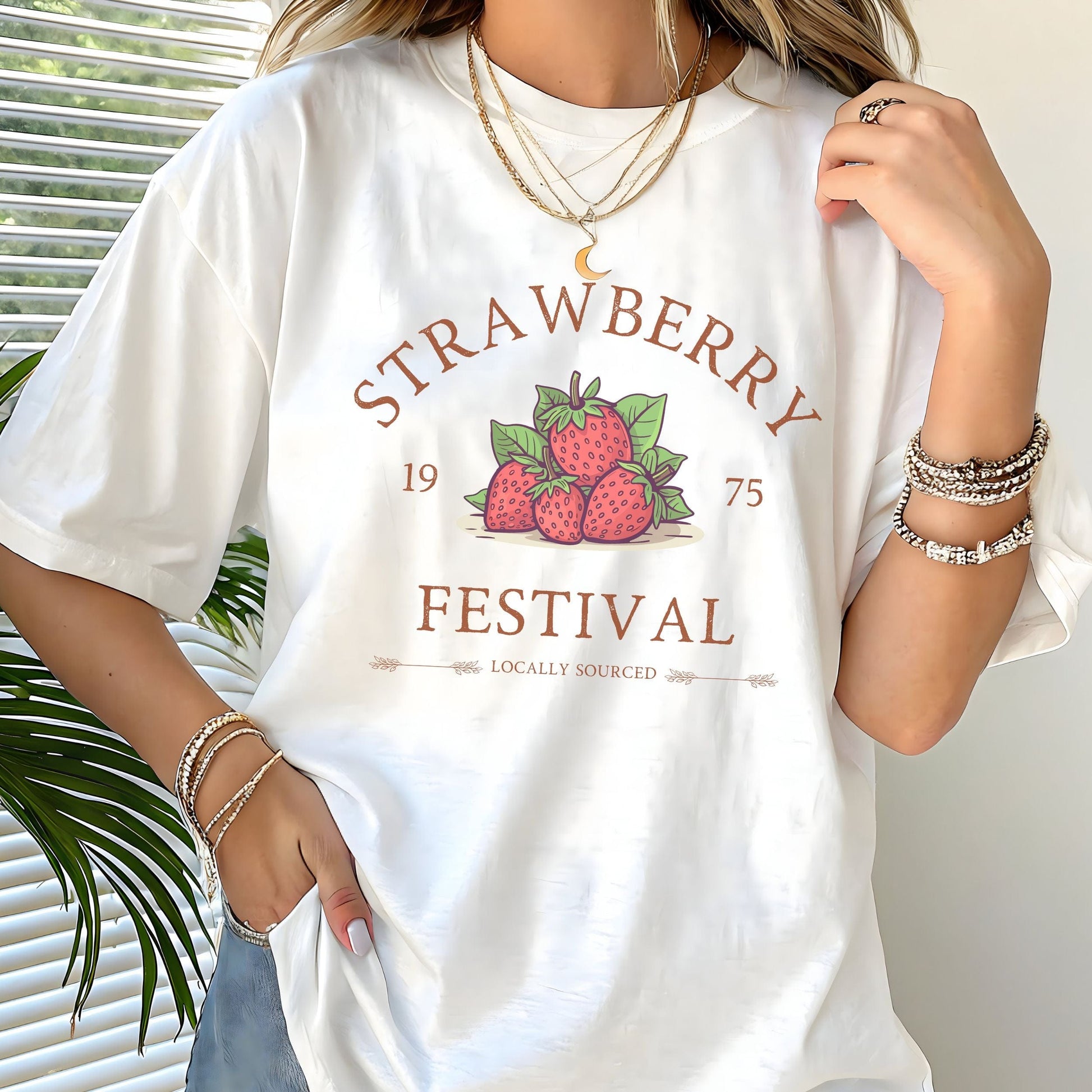 “Strawberry Festival” t-shirt with a vintage berry illustration, arched retro text, and “locally sourced” detail in rustic tones.