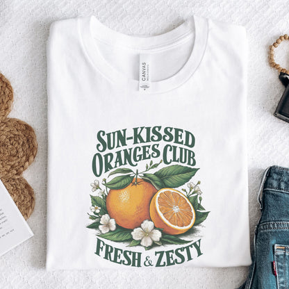 T-shirt design with vintage "Sun-Kissed Oranges Club" text, featuring a bright orange with blossoms and greenery, labeled “Fresh & Zesty.”