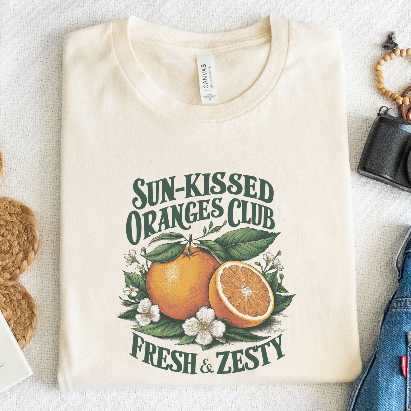 T-shirt design with vintage "Sun-Kissed Oranges Club" text, featuring a bright orange with blossoms and greenery, labeled “Fresh & Zesty.”