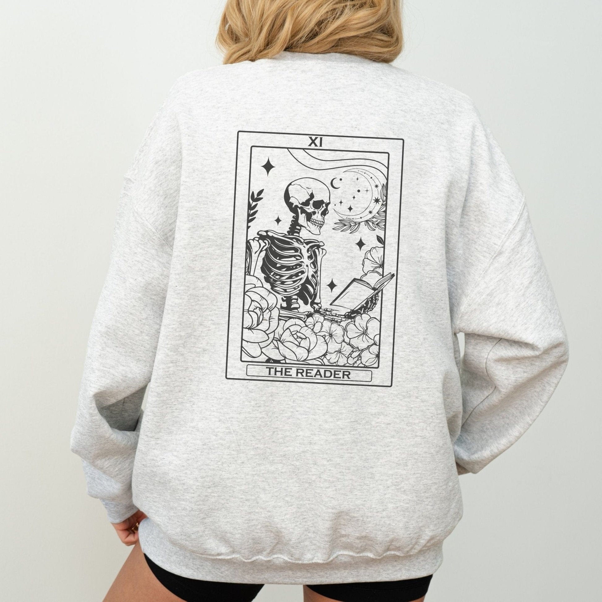 “The Reader Tarot” sweatshirt with mystical tarot card illustration printed on the back, perfect for book lovers and cozy fall vibes.