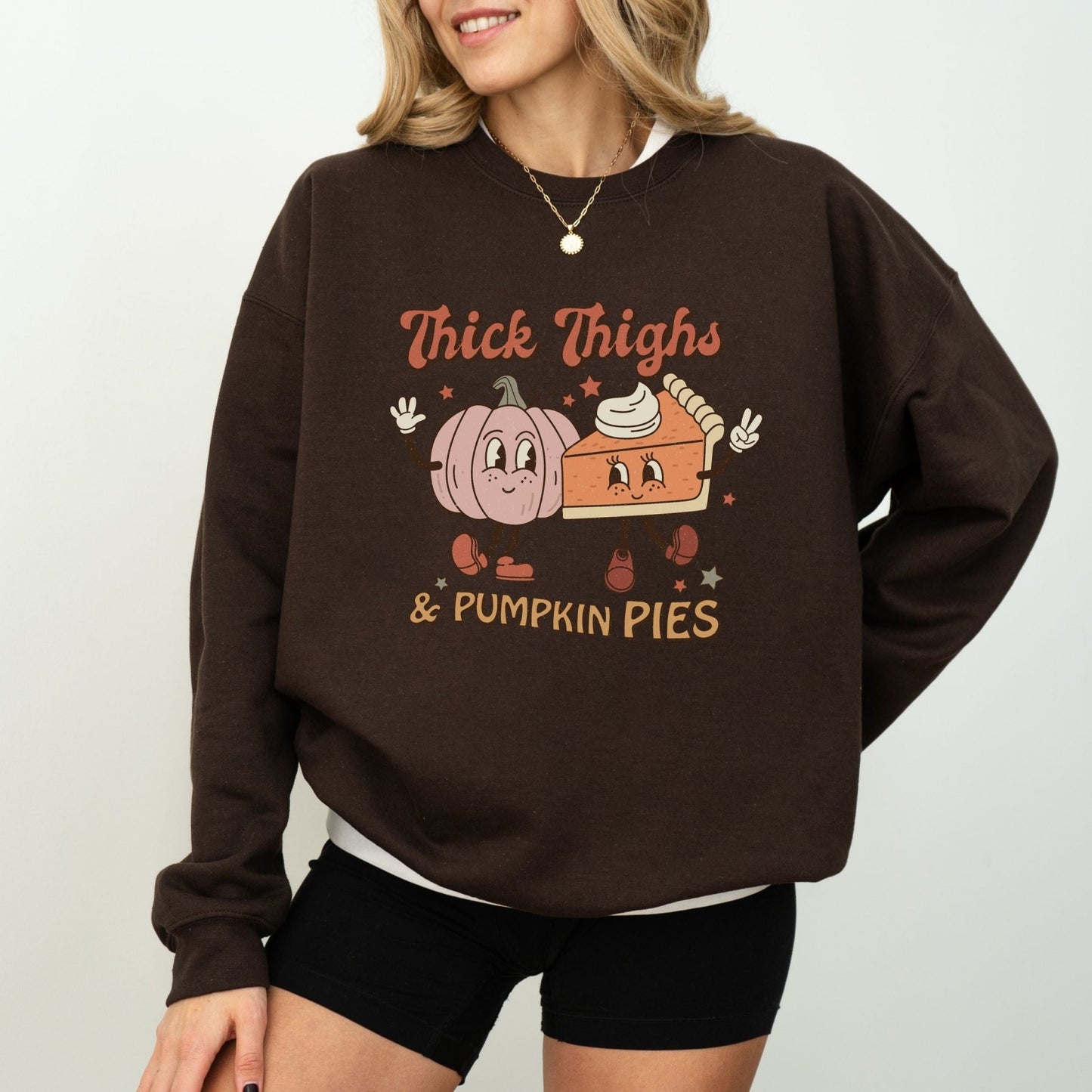 Thanksgiving sweatshirt with "Thick Thighs & Pumpkin Pies" graphic featuring pumpkin and pie characters.