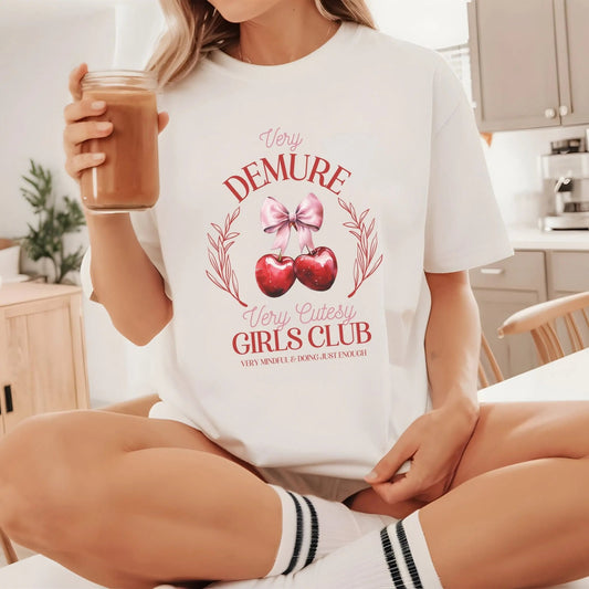 Very Demure, Very Cutesy Girls Club t-shirt with cherry design, perfect for coquette style.