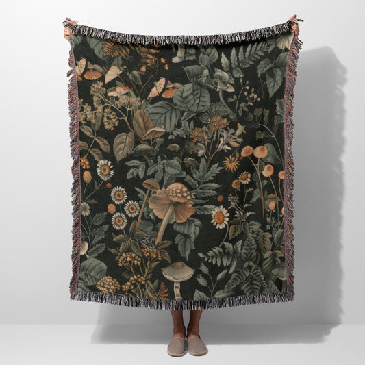 Woodland botanical fringe blanket with mushroom and wildflower print, cozy cottagecore decor.